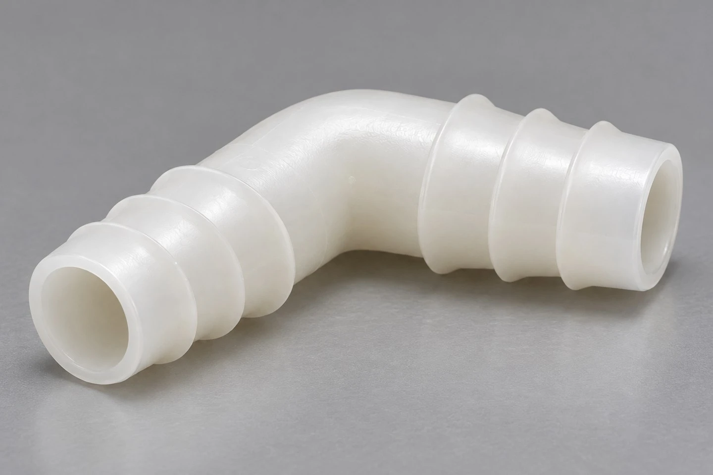 product-1-1 Side view of a custom PP hose elbow connector showing the bend and two perpendicular barbed interfaces